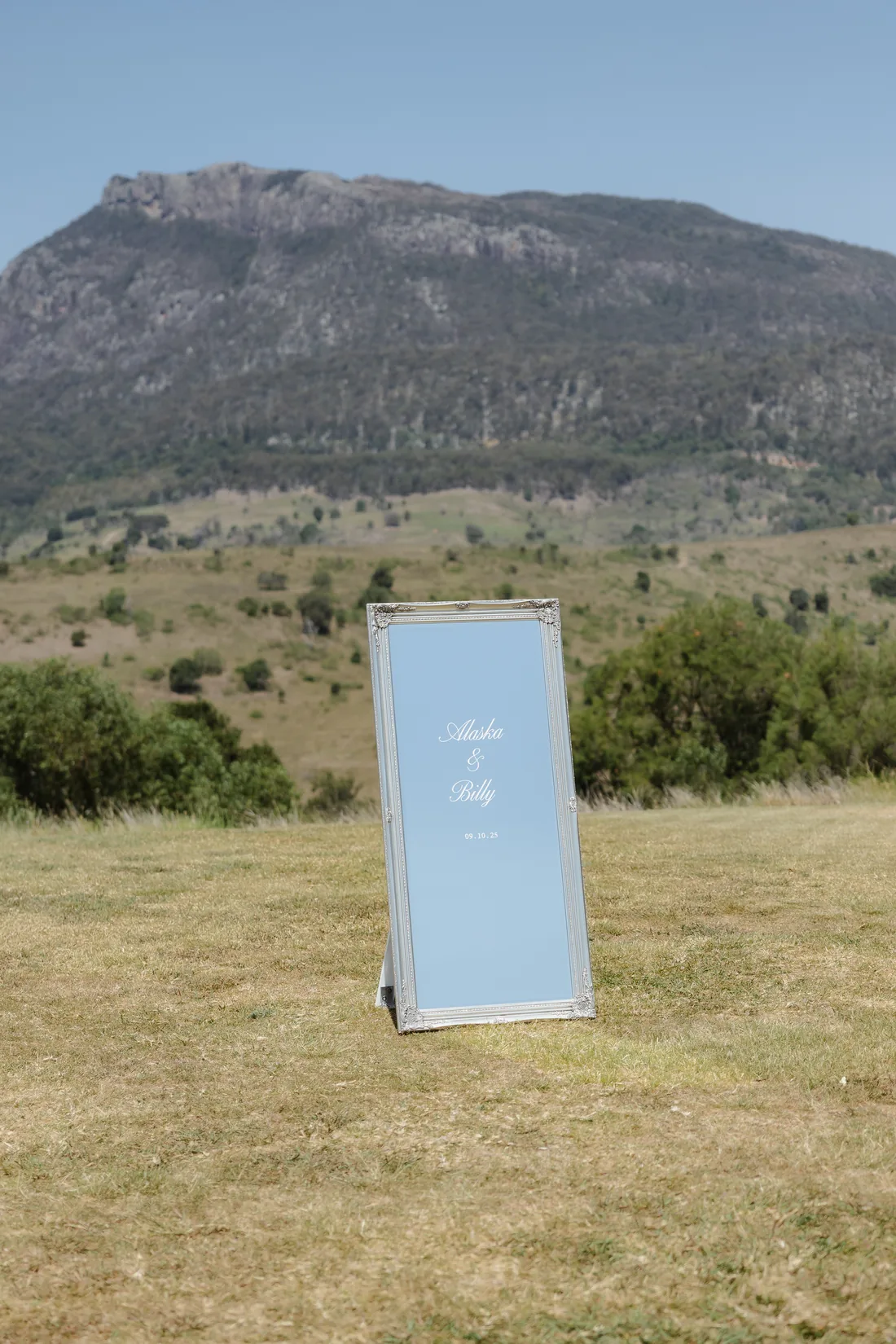 Alaska and Billy wedding welcome sign in a vintage mirror frame, mountain backdrop