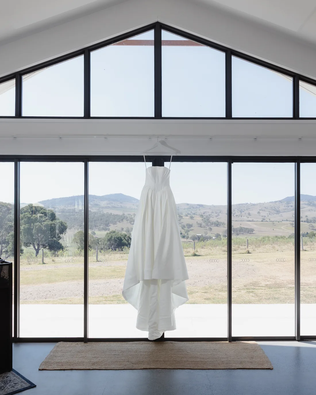 Wedding dress hanging in the gable window with sweeping countryside views