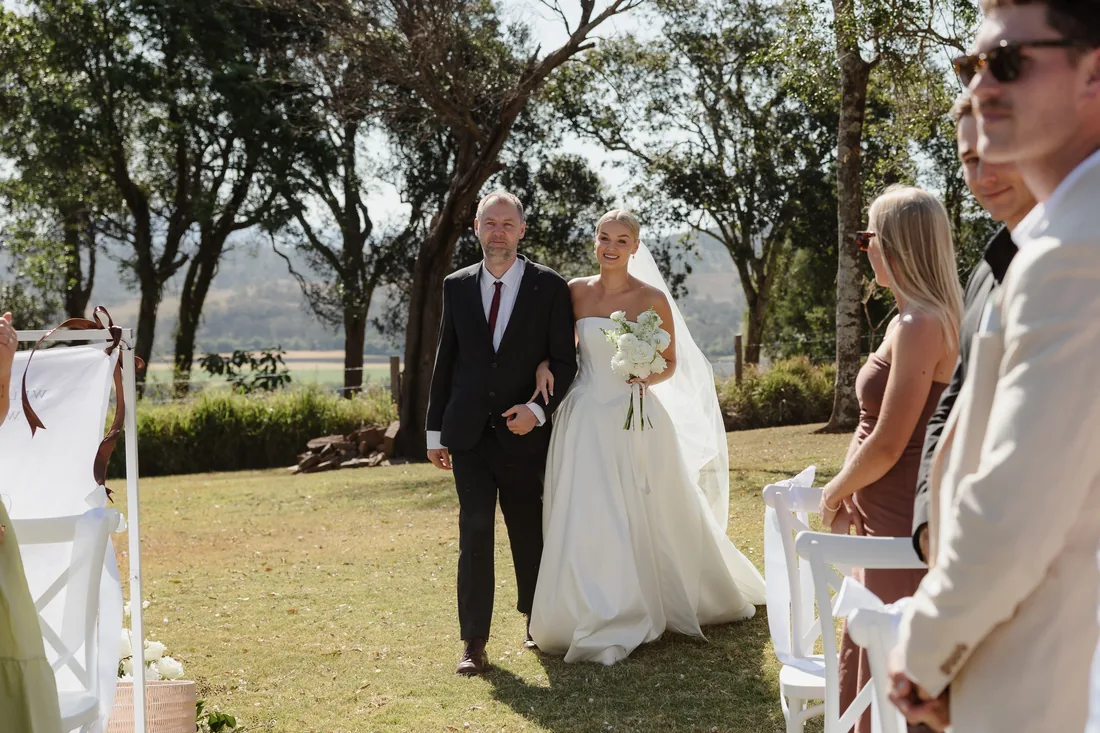 Bride walking down the aisle with her father, guests seated either side