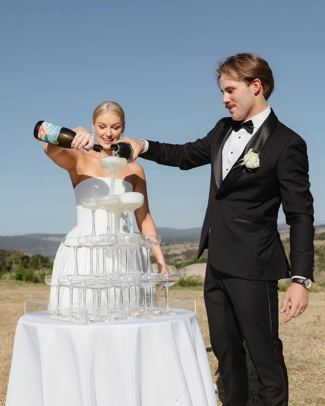 Bride and groom pouring champagne into a tower of glasses together