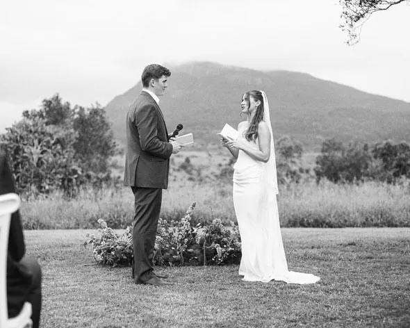 Alex and Will exchanging vows during their ceremony, Scenic Rim mountains behind them