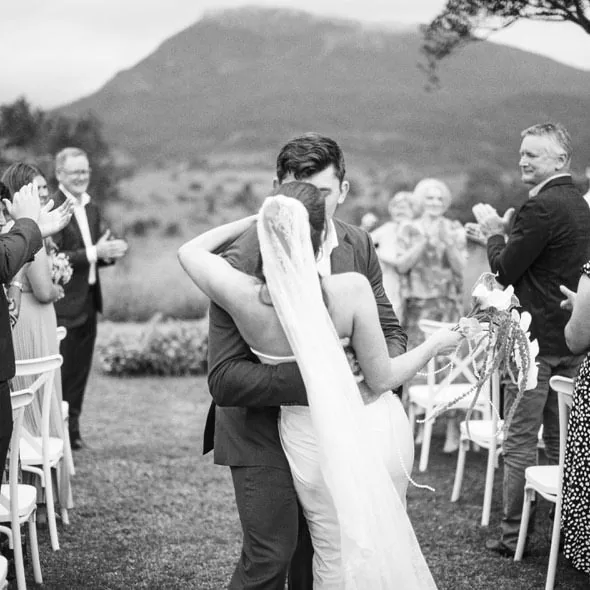 Black and white photo of guests applauding as Will dips Alex for a kiss