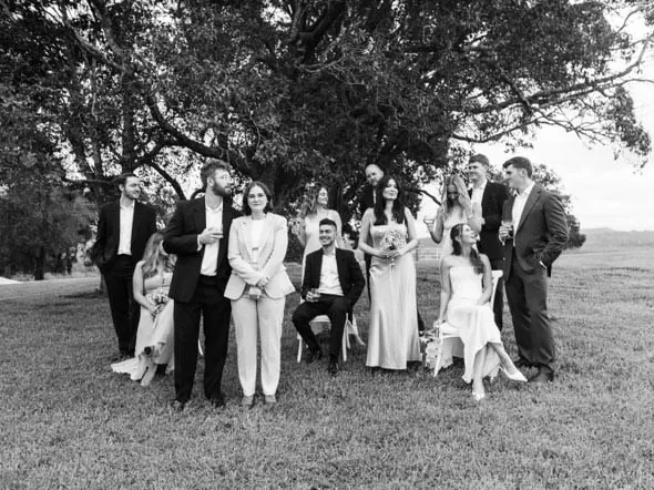 Black and white group photo of the bridal party beneath a large tree