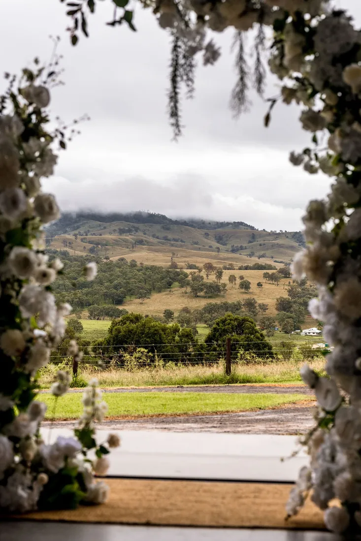 View of the misty hills through a floral-draped doorway