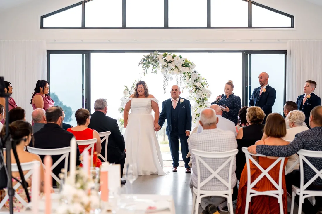 Carrie and Chris holding hands as they walk into the reception room to applause