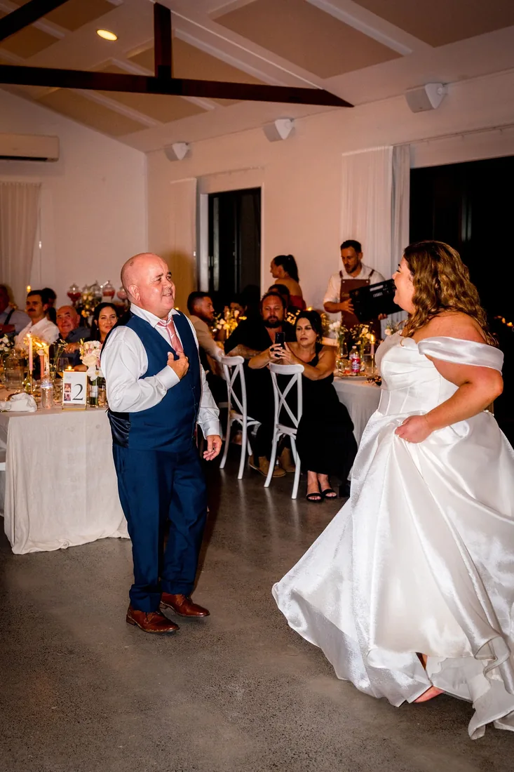 Carrie laughing and dancing with her father in the reception room at night