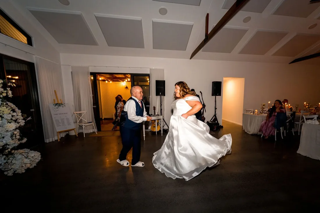 Carrie and her father dancing together in the reception room as guests look on