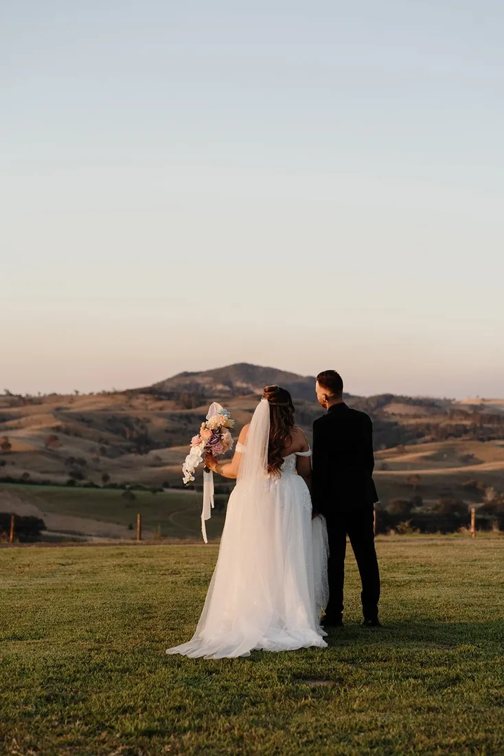 Chelsea and Rhys looking out over the rolling hills at sunset