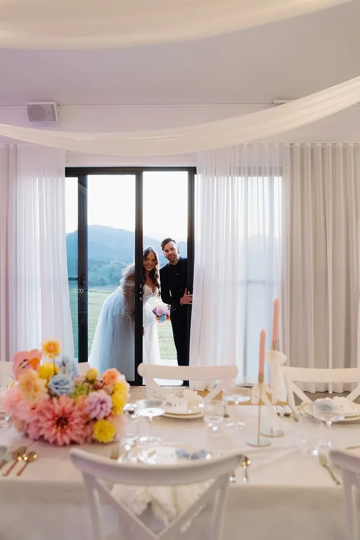 Chelsea and Rhys arriving at the reception doorway, greeted by the flower-filled table