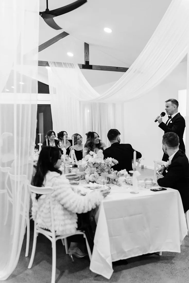 Black and white photo of the best man giving a speech during reception dinner