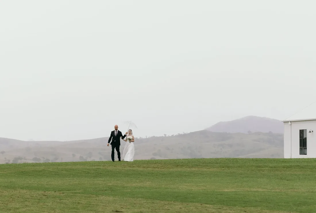 Daniel and Emily walking together across the misty lawn towards the reception building
