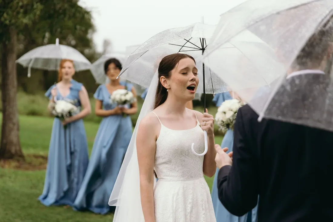 Emily crying happy tears as Daniel holds an umbrella over her during the ceremony