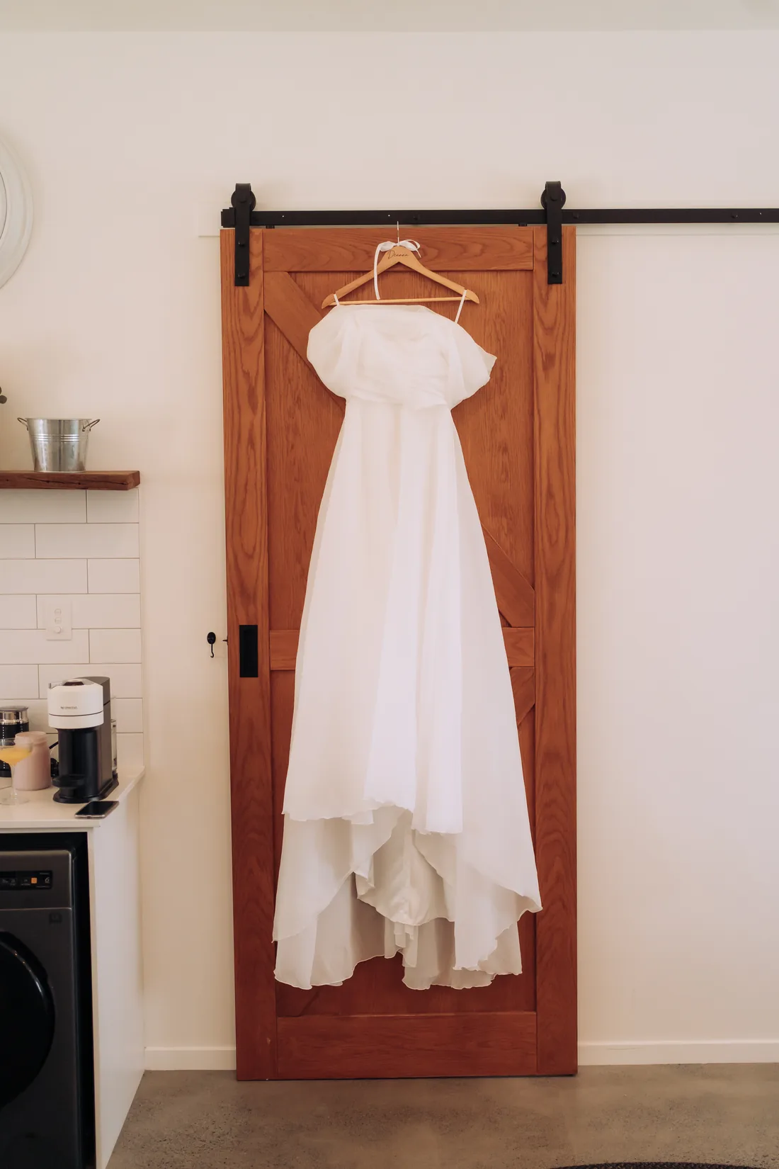 Wedding dress hanging on a timber barn door before the ceremony