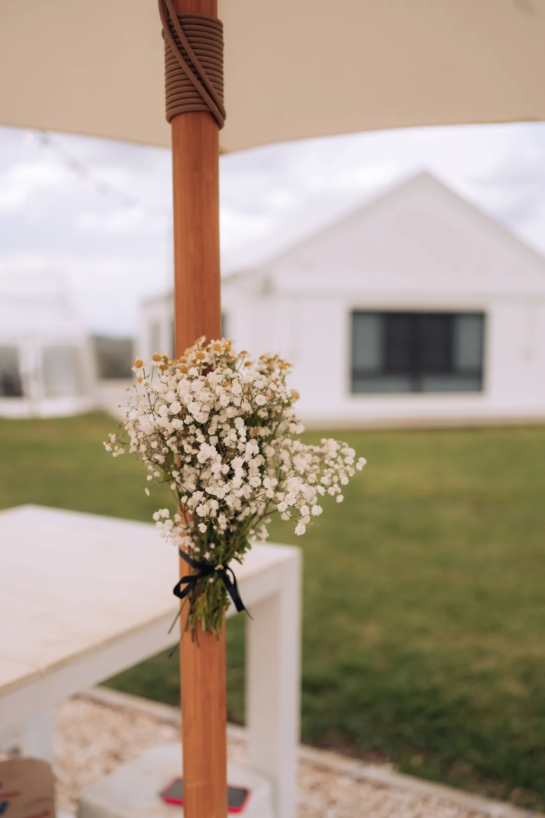 Close-up of baby's breath tied to a market umbrella post with black ribbon