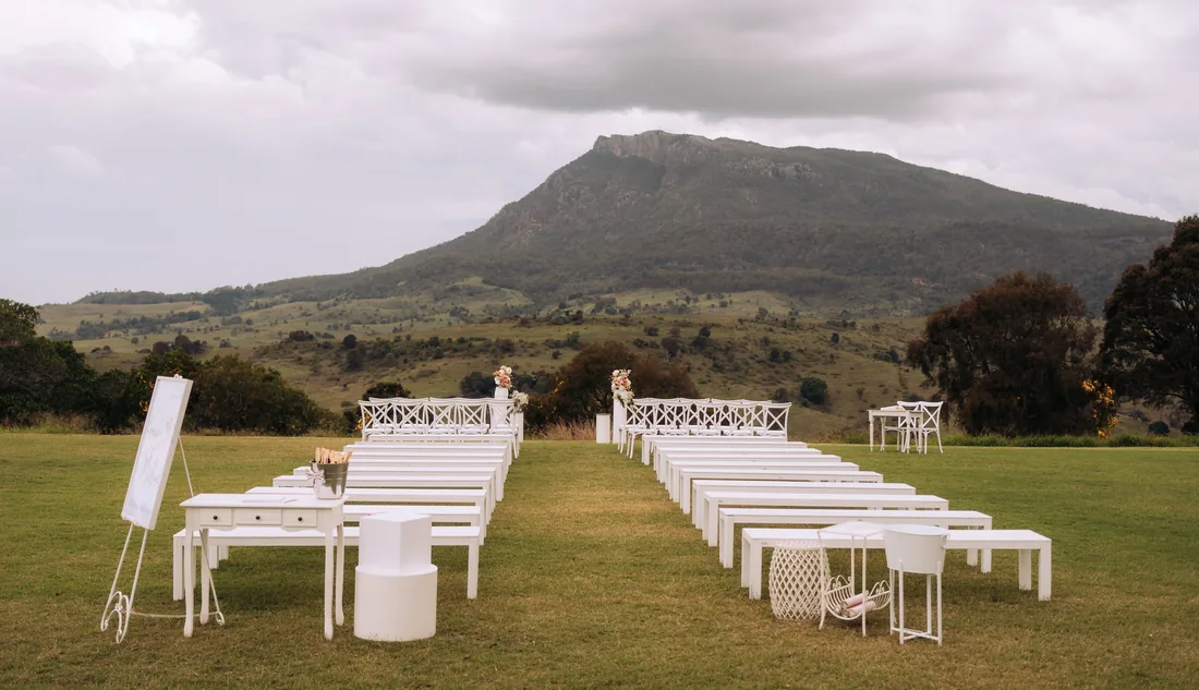 Rows of empty white ceremony benches facing the mountain