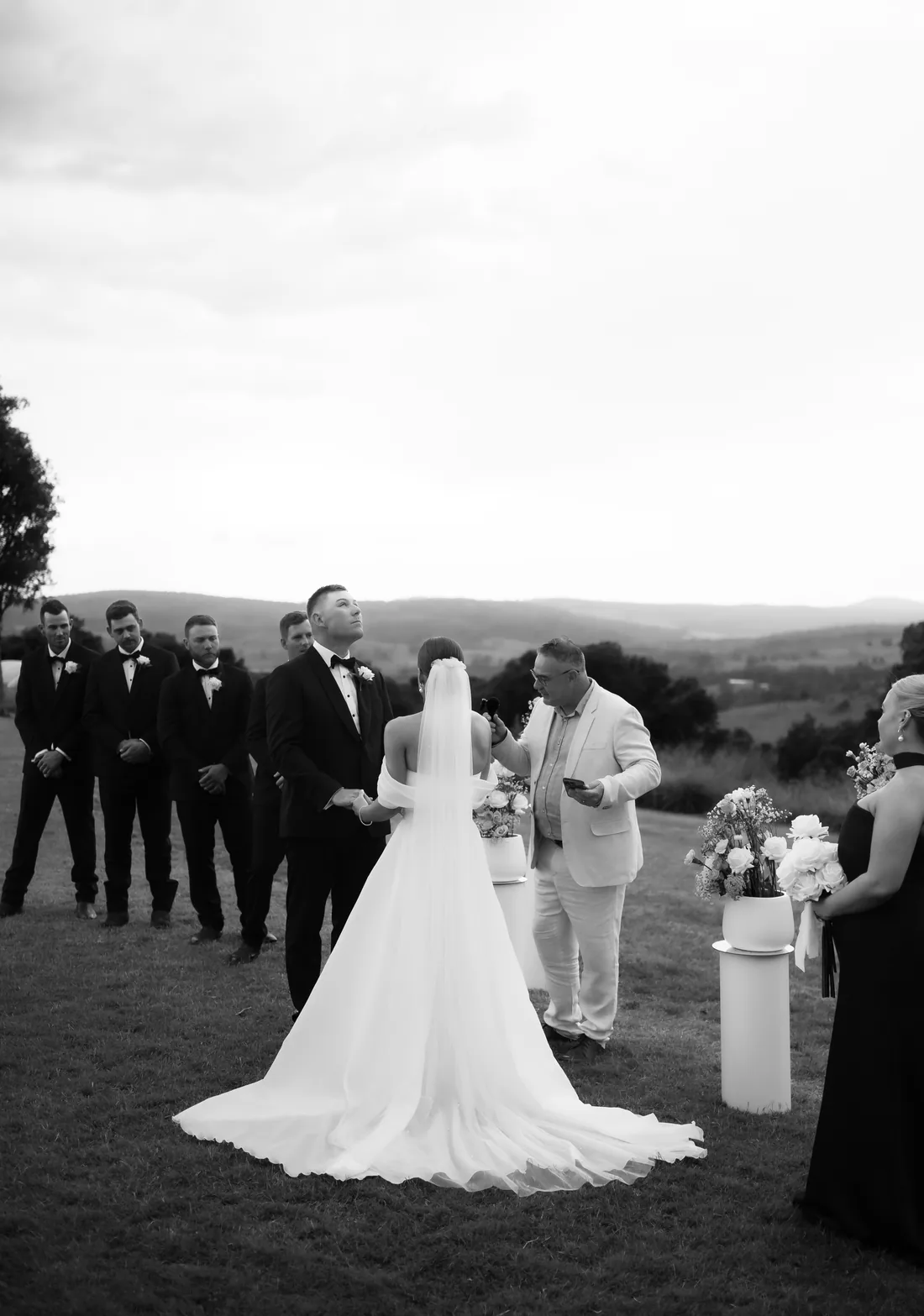 Black and white photo of Deanna and Michael during their vows, groomsmen and mountain views behind