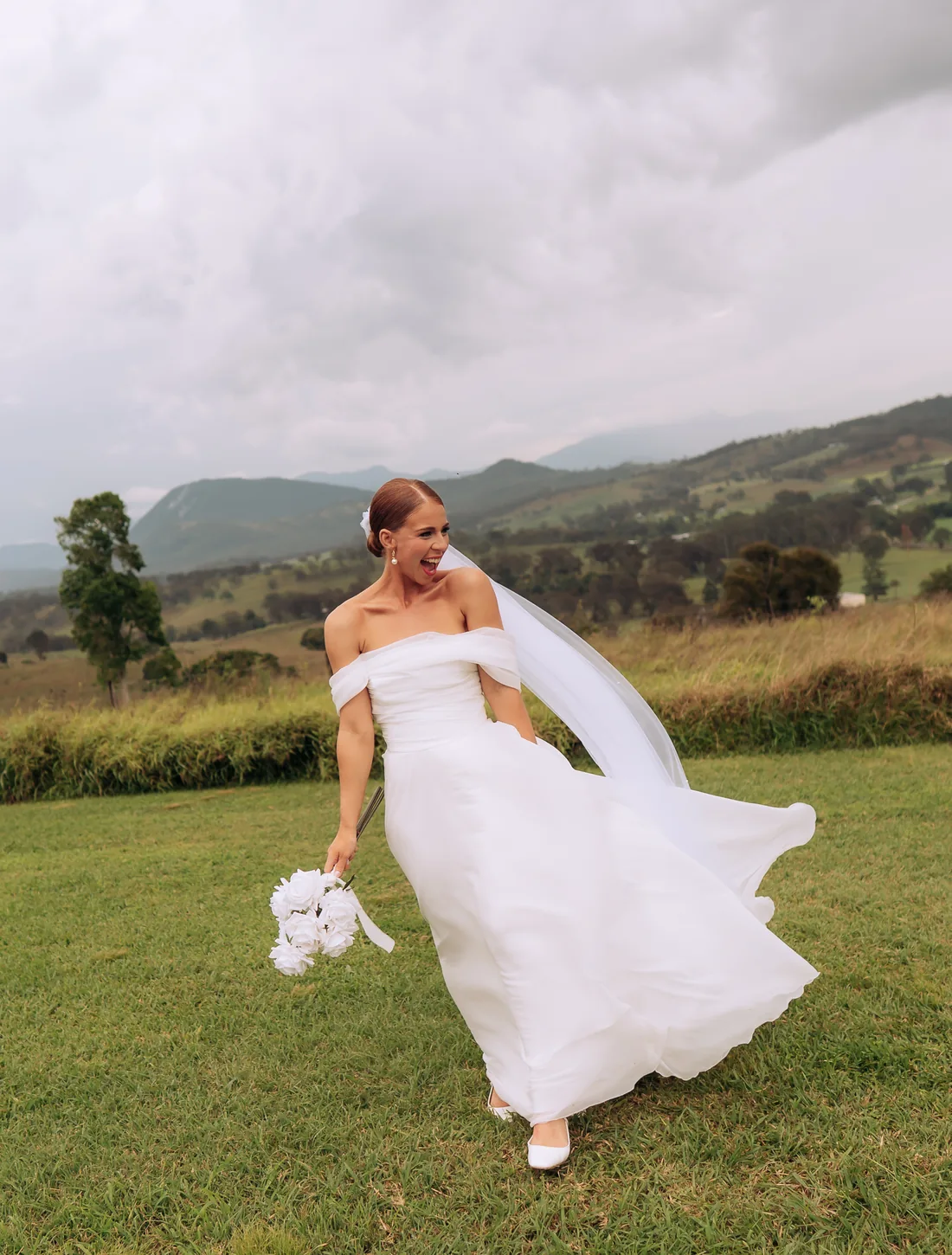 Deanna twirling in her gown on the lawn, veil billowing, stormy sky behind