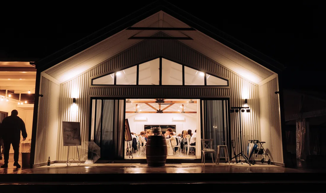 The reception barn lit up at night with guests seated inside