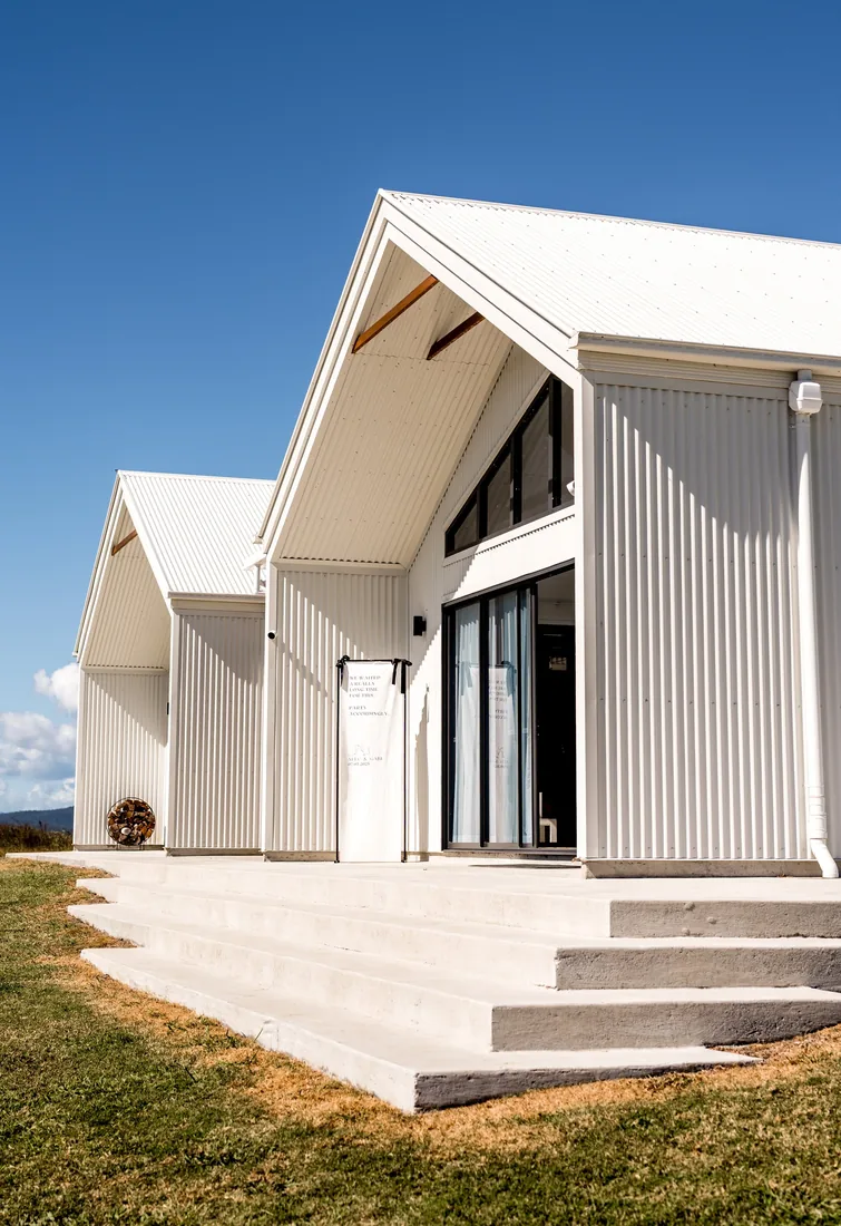 Exterior of the white gable-roofed reception venue under a clear blue sky