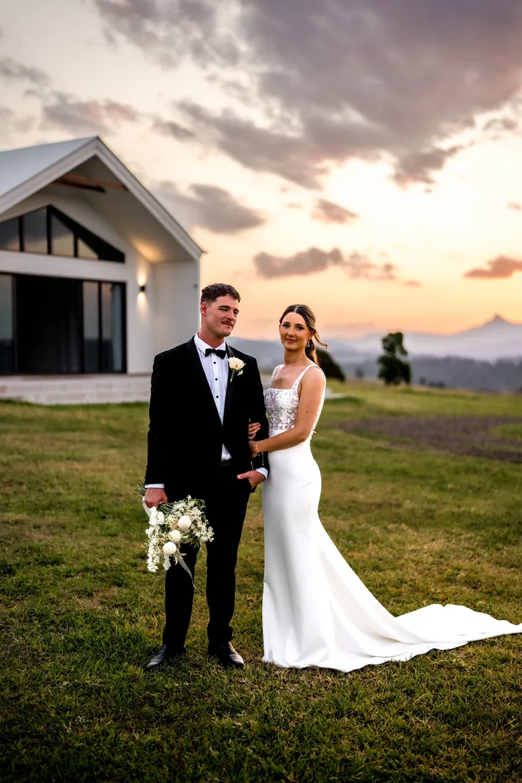 Georgia and Nick standing in front of the reception building at sunset