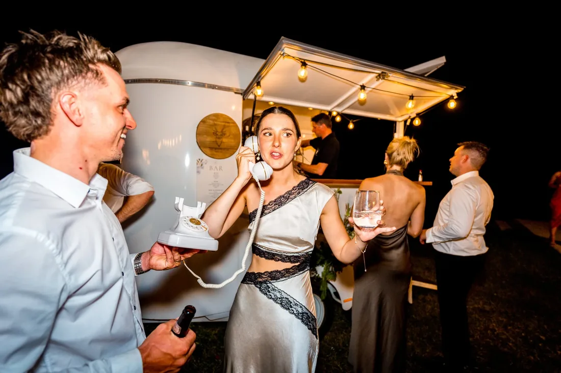 Guests laughing and dancing beside the reception bar caravan at night