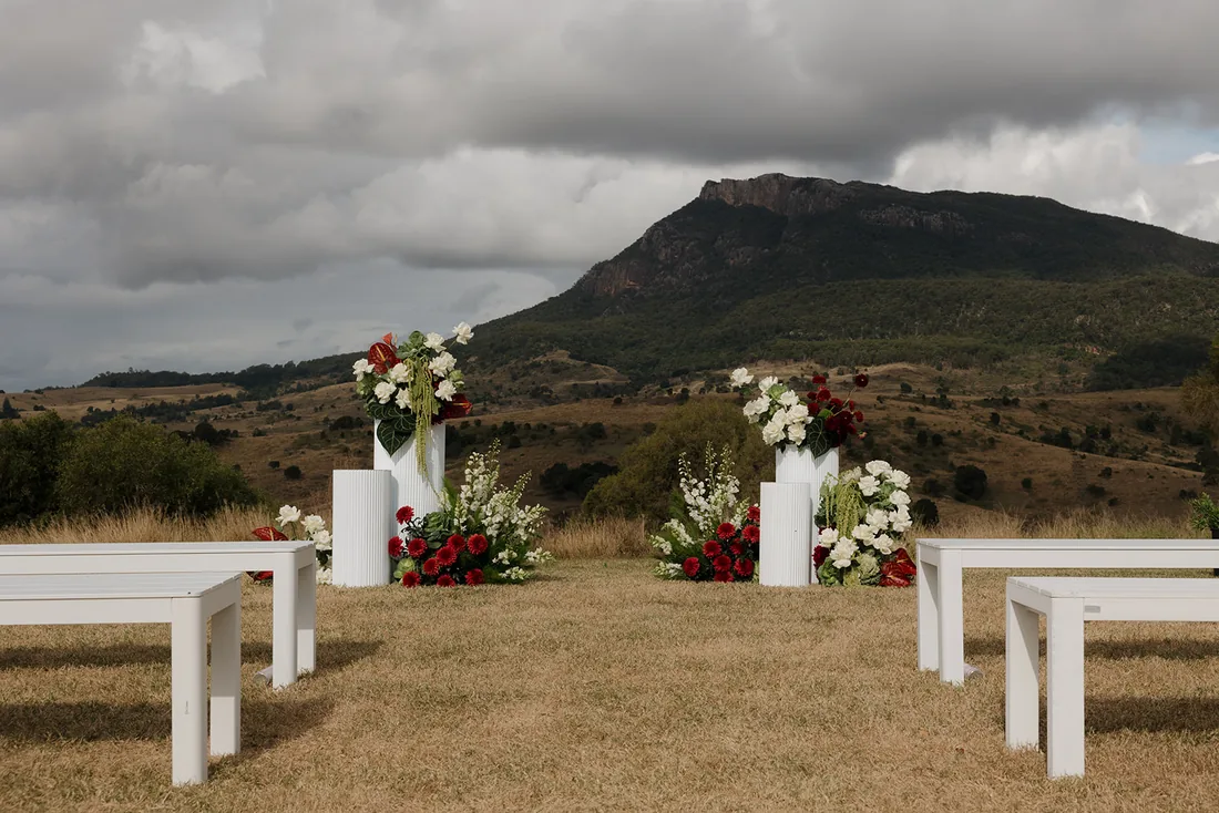 Ceremony floral pillars with burgundy and white blooms, mountain backdrop