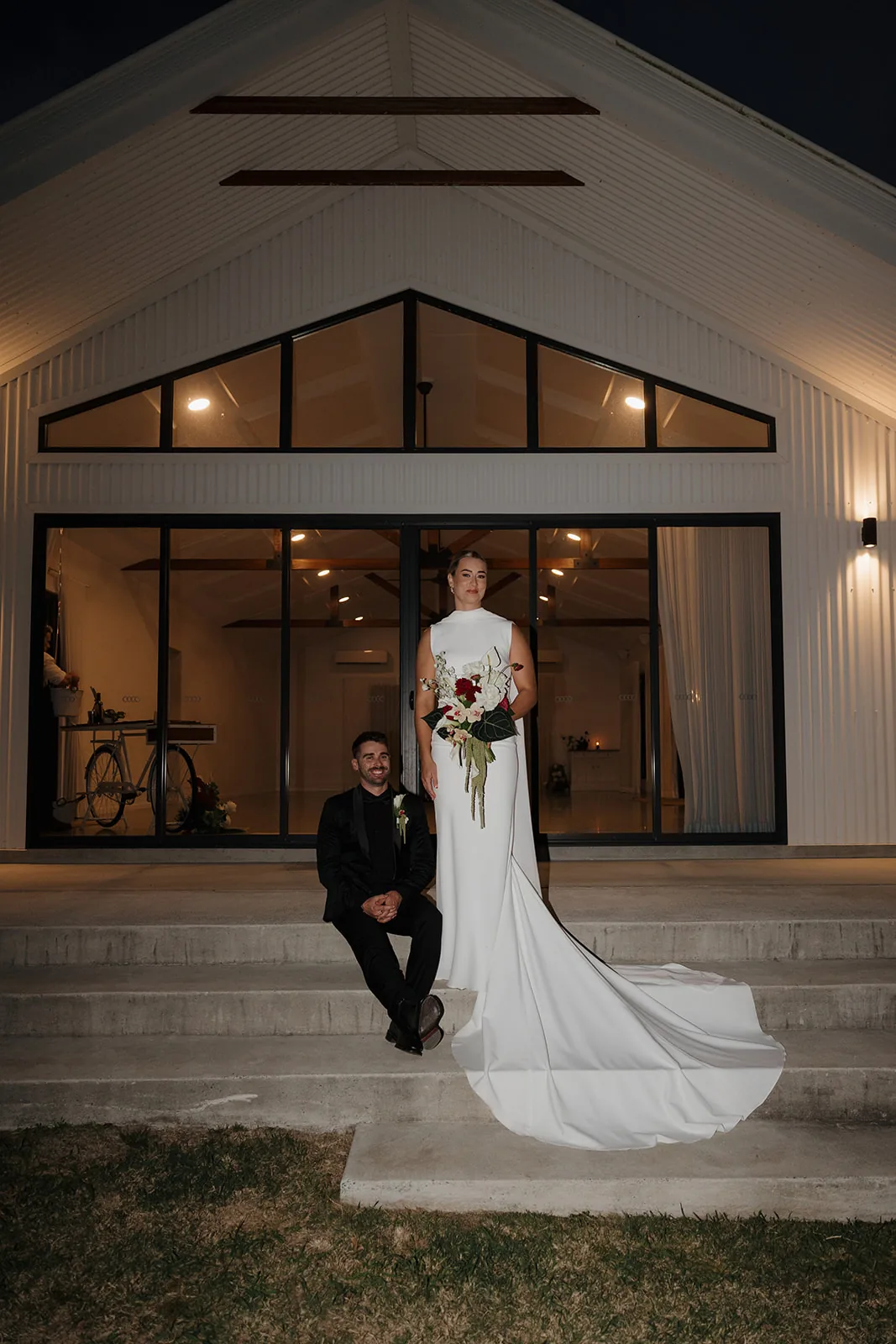 Cory sitting on the venue steps as Jess stands beside him at night