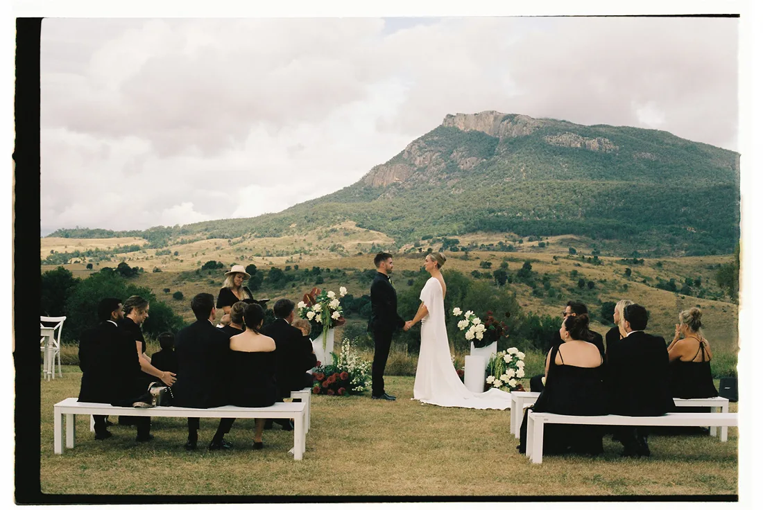 Vintage-style photo of Jess and Cory exchanging vows, mountain backdrop