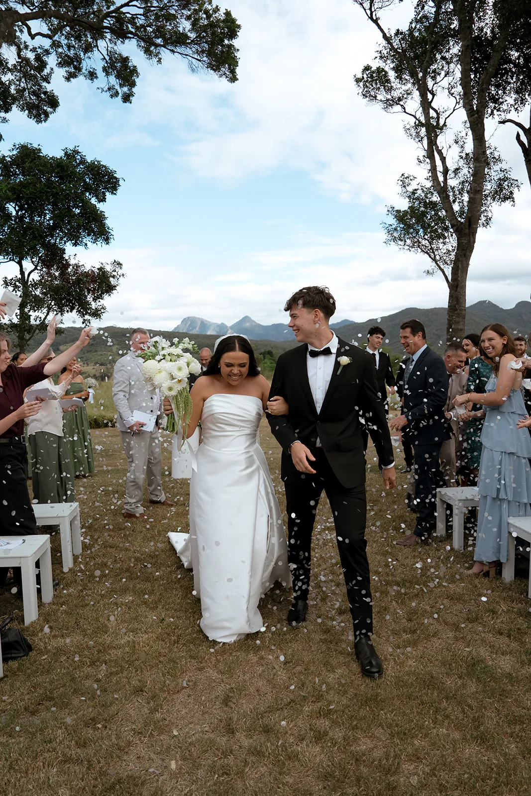 Jodi and Frank walking through confetti after their ceremony, guests celebrating either side