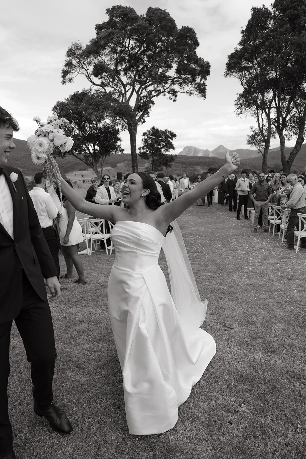 Black and white photo of Jodi cheering with her arms raised after the ceremony