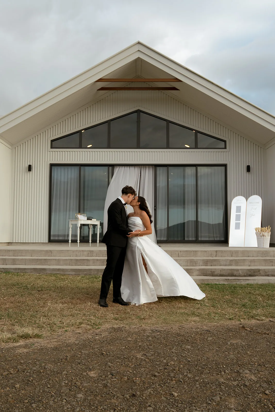 Jodi and Frank kissing outside the reception building at dusk