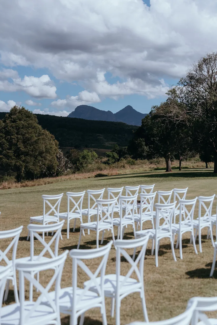 Empty white ceremony chairs facing the mountain range at Maroon Hill Estate