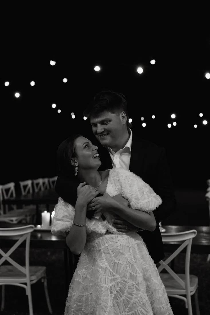 Jorjia and James embracing at night under festoon lighting