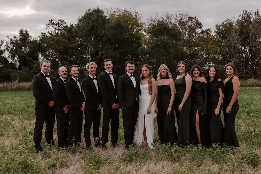 Bridal party gathered either side of Karly and Anru in the field