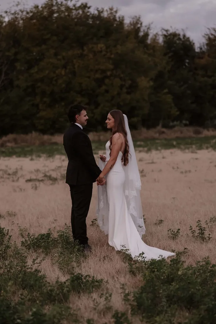 Karly and Anru holding hands facing each other in a golden paddock at dusk