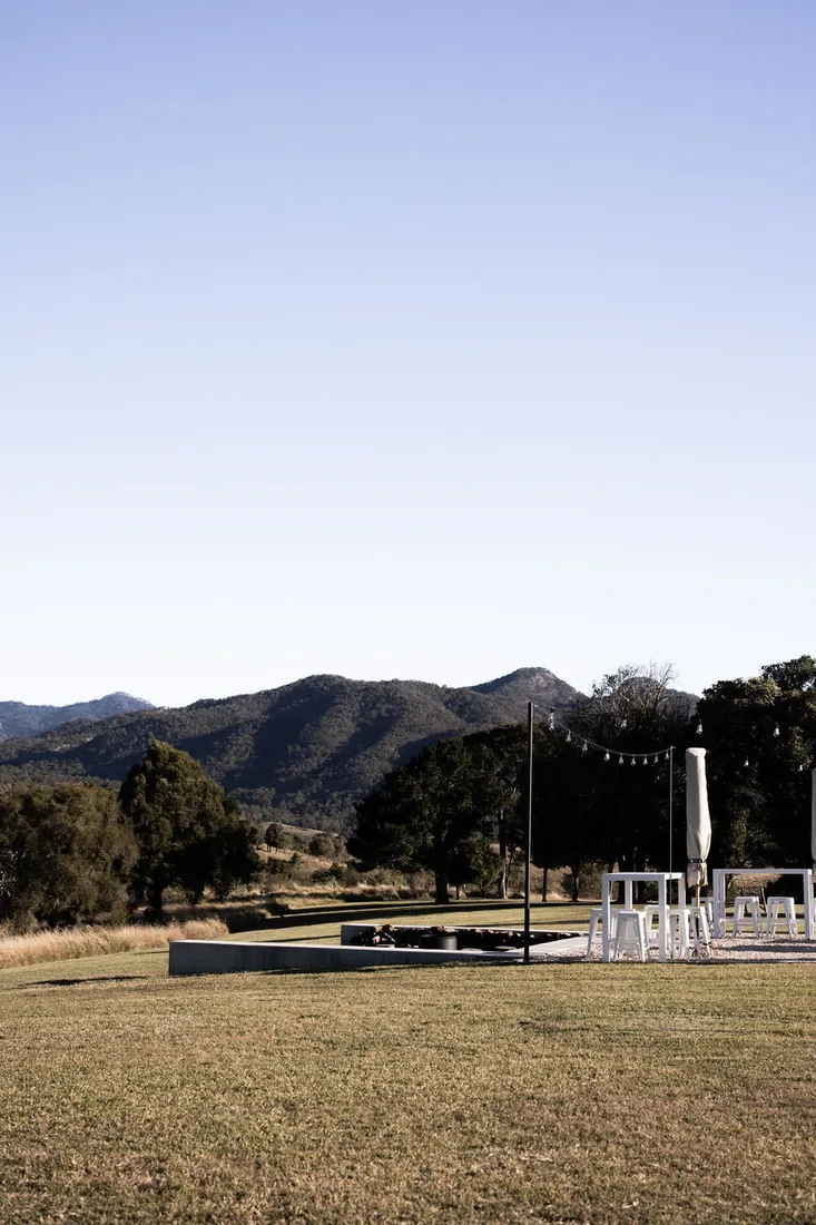 Wide view of the ceremony and cocktail setup at dusk with mountains behind at Maroon Hill Estate