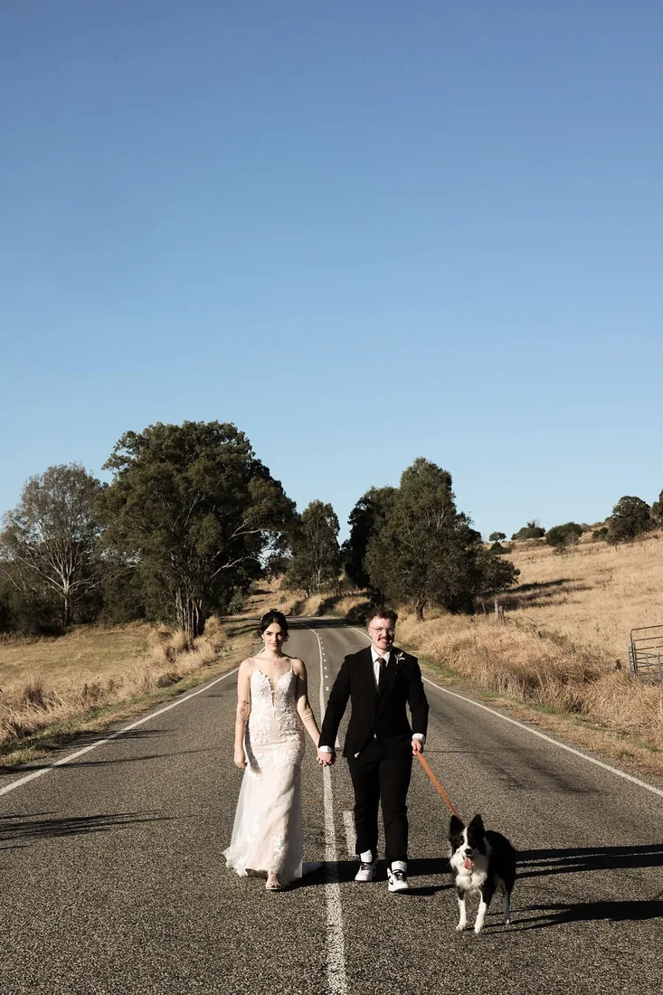 Kate and Jacob walking down a country road holding hands with their dog on a lead