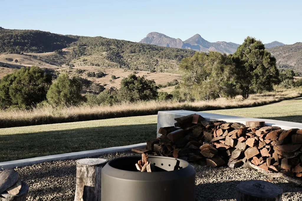 Outdoor firepit with stacked firewood overlooking the mountains