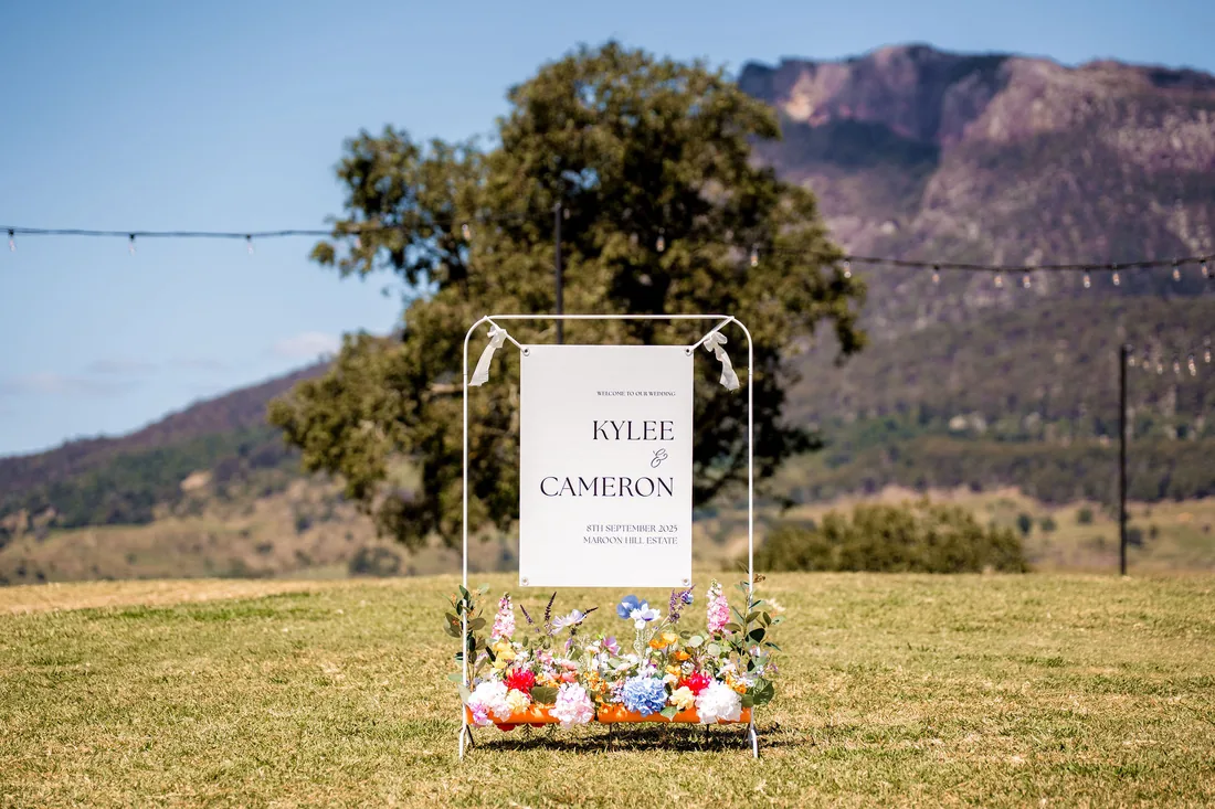 Kylee and Cameron wedding welcome sign with colourful wildflowers, mountain backdrop