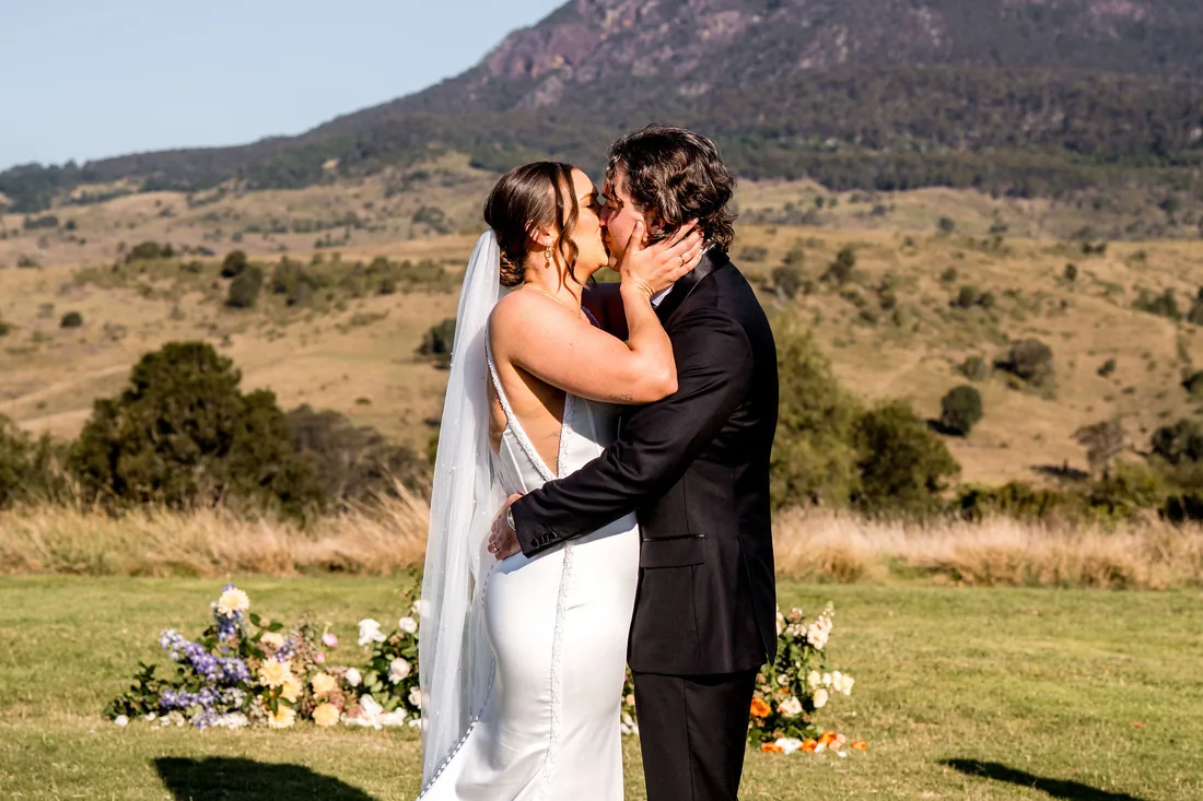 Kylee and Cameron kissing at the altar, mountain views behind