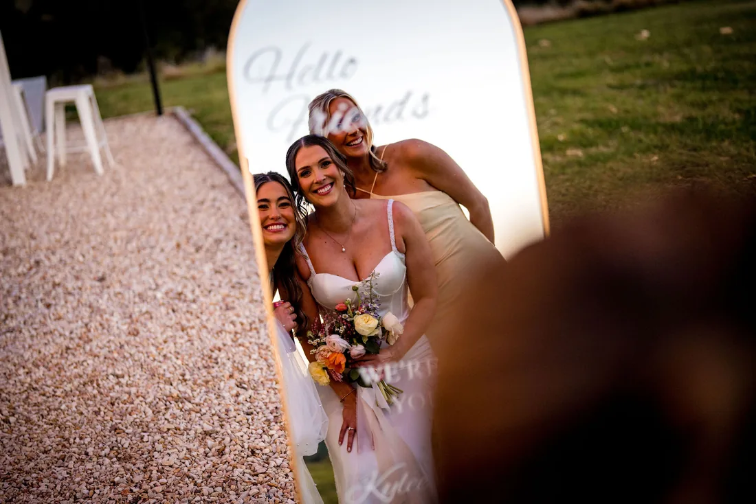 Kylee laughing with her bridesmaids in front of a Hello Friends mirror sign