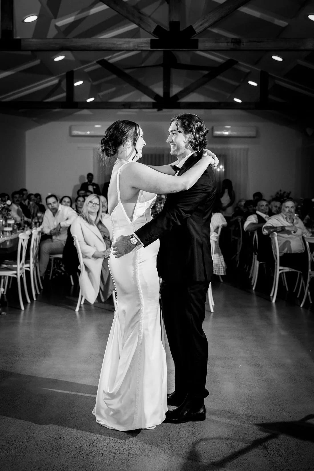 Black and white photo of Kylee and Cameron sharing their first dance in the reception room