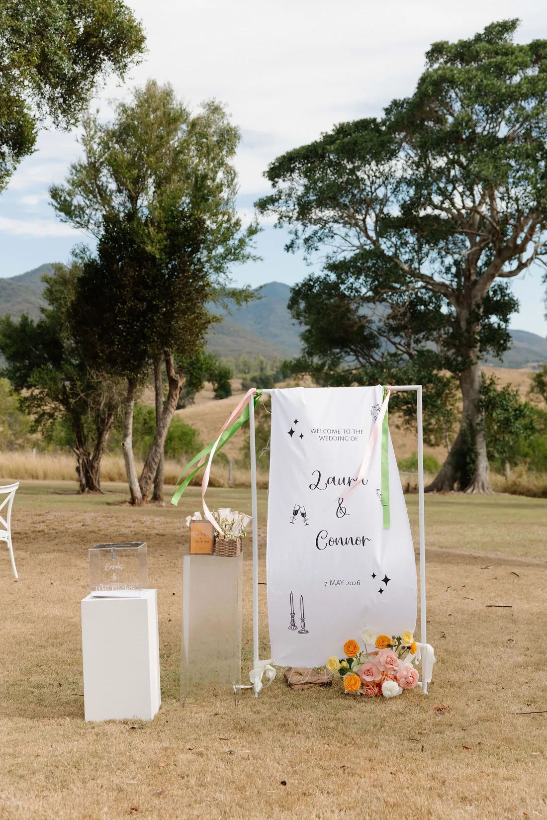Laura and Connor wedding welcome banner styled with ribbons and fresh florals, mountain backdrop