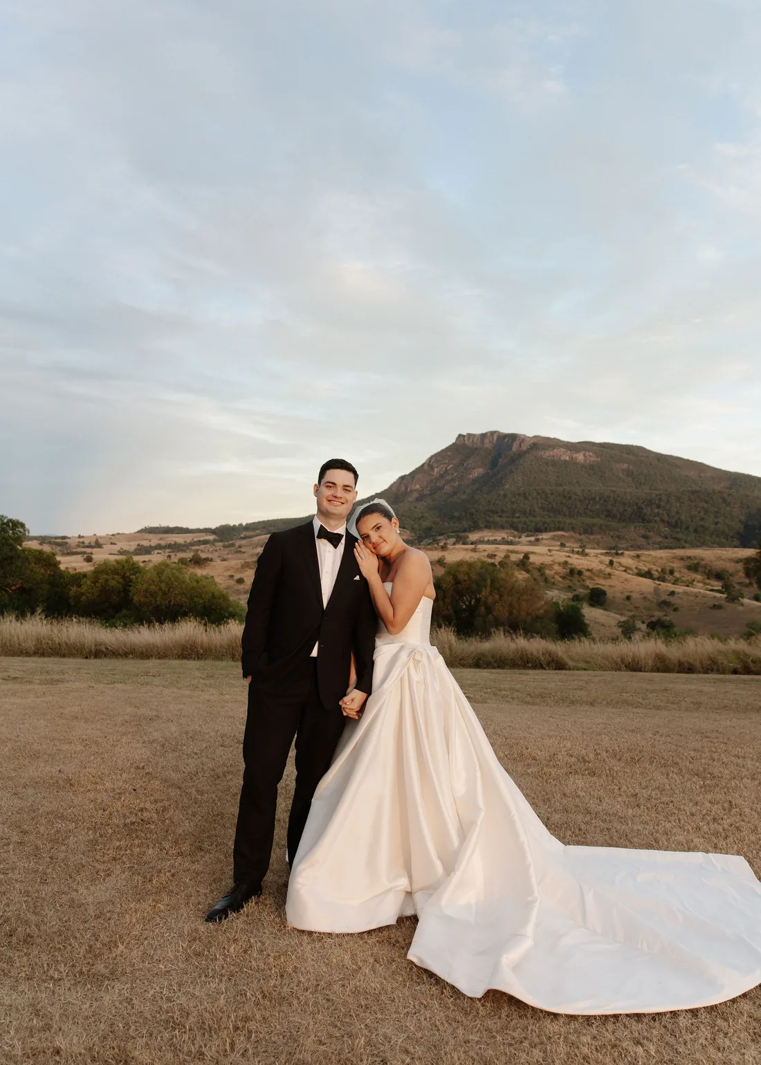 Connor and Laura embracing outdoors, mountain views behind