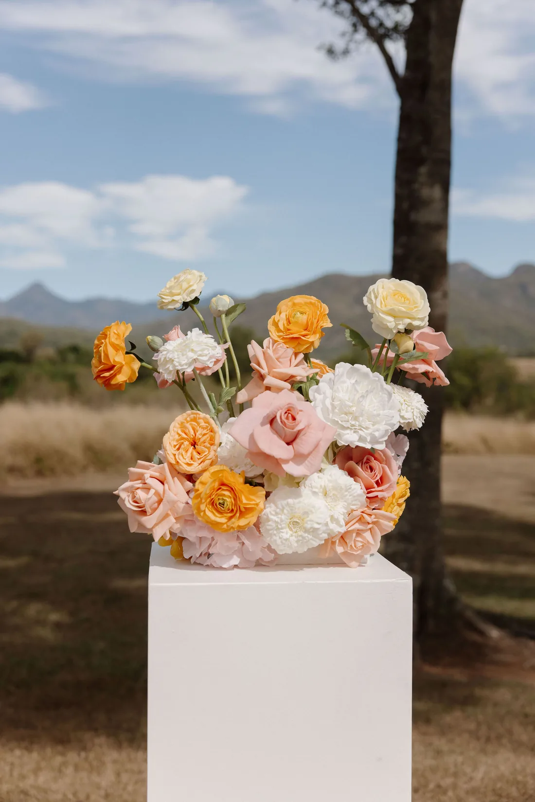 Close-up of a peach, pink and white floral arrangement on a white plinth