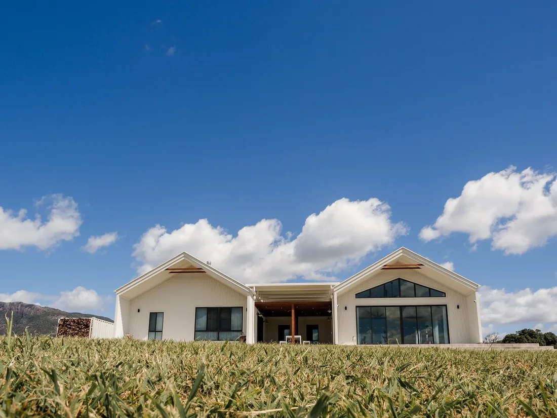 Exterior of the white farmhouse-style venue at Maroon Hill Estate under a bright blue sky