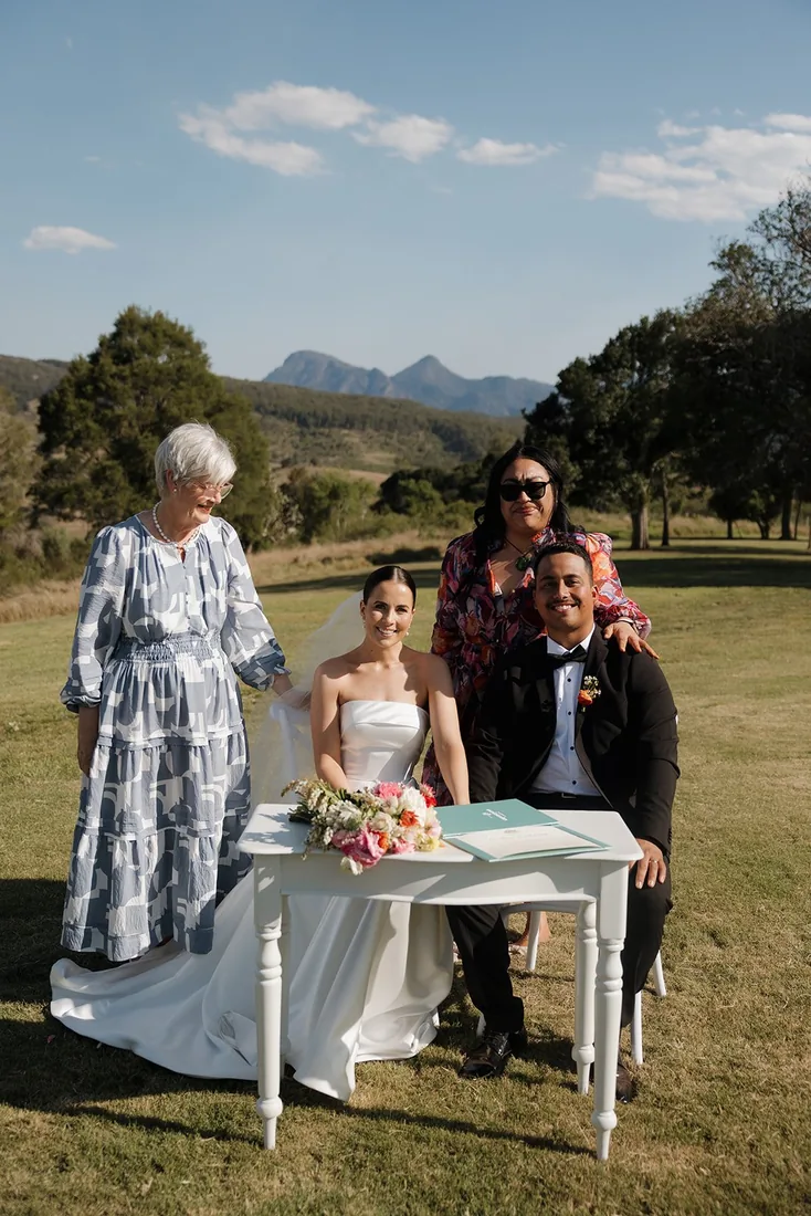 Family members with the celebrant at the signing table, mountain range in the background