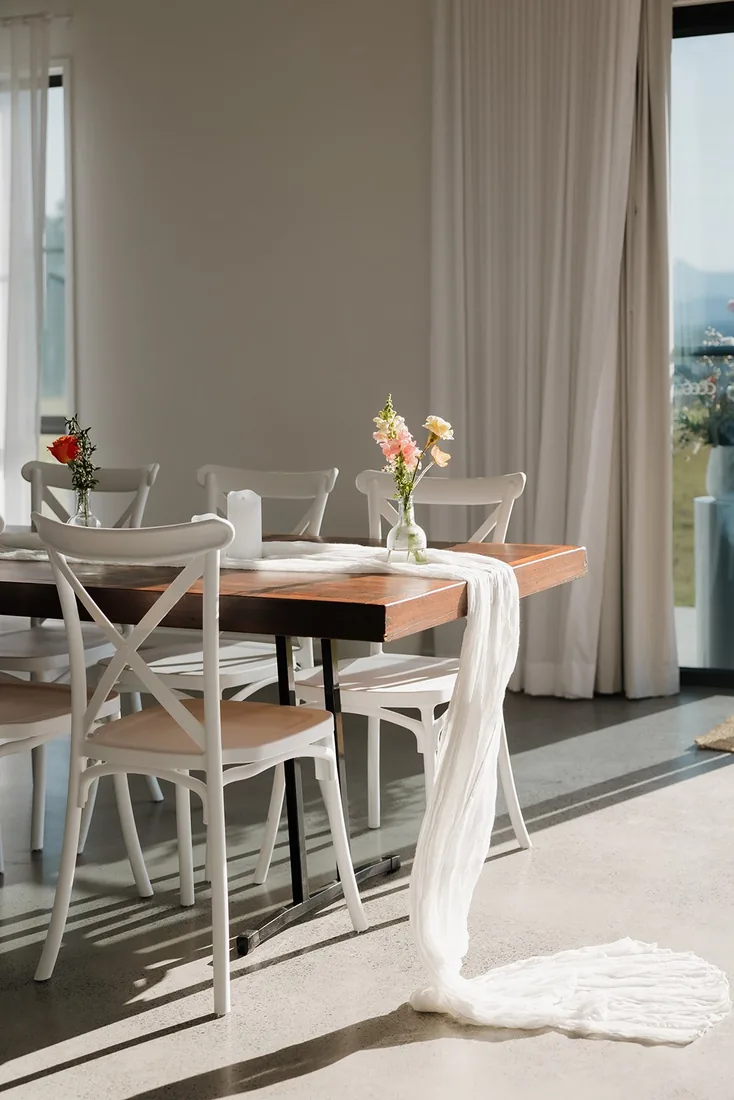 Sunlit indoor dining table set with wildflowers and a white linen table runner