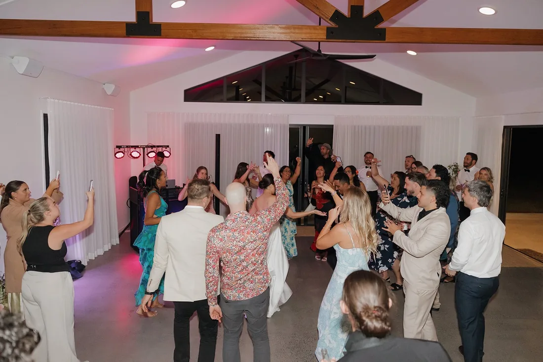 Guests dancing indoors under pink lighting at the reception