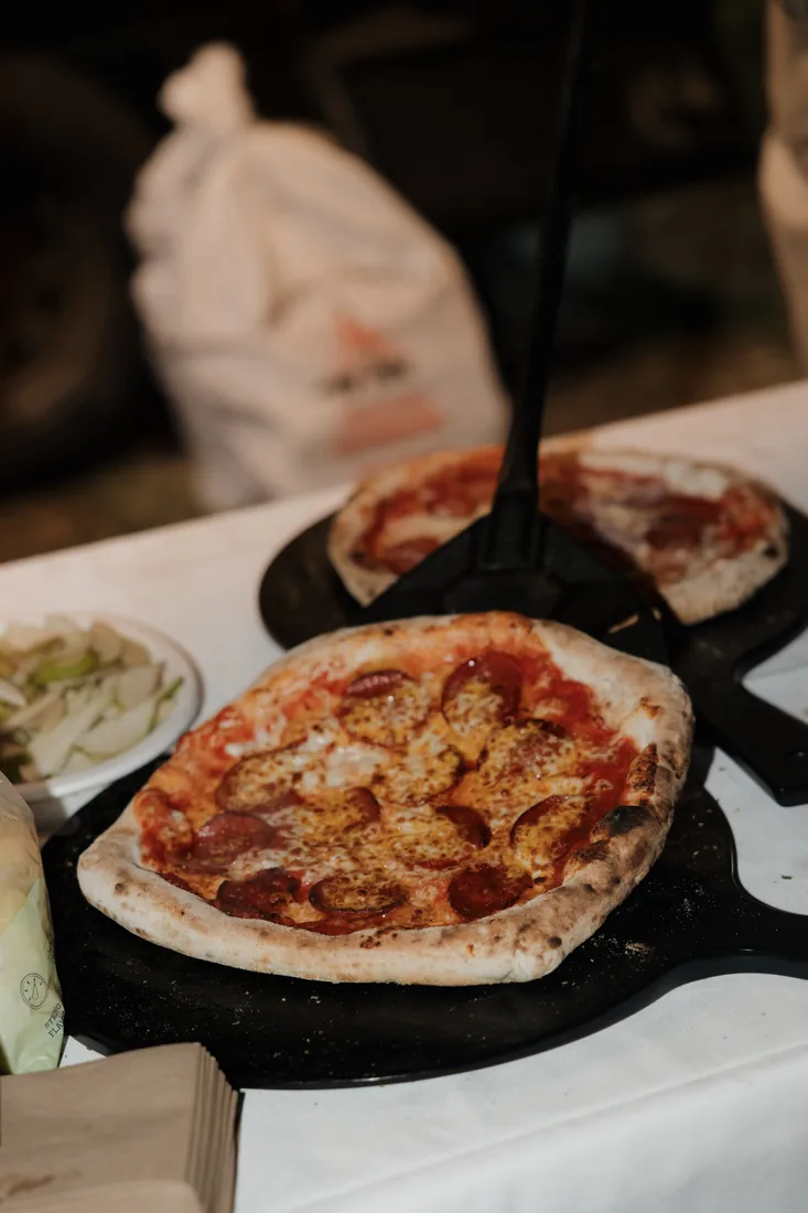 Pepperoni pizza fresh from a wood-fired oven on a catering peel
